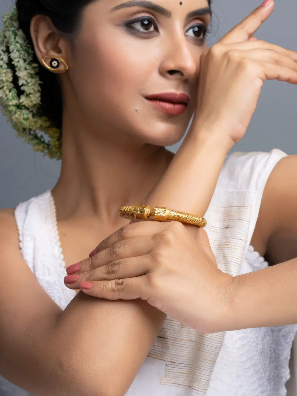 South Asian woman in white ethnic dress wearing LOOK AND ADORN gold plate bangle and floral hair garland