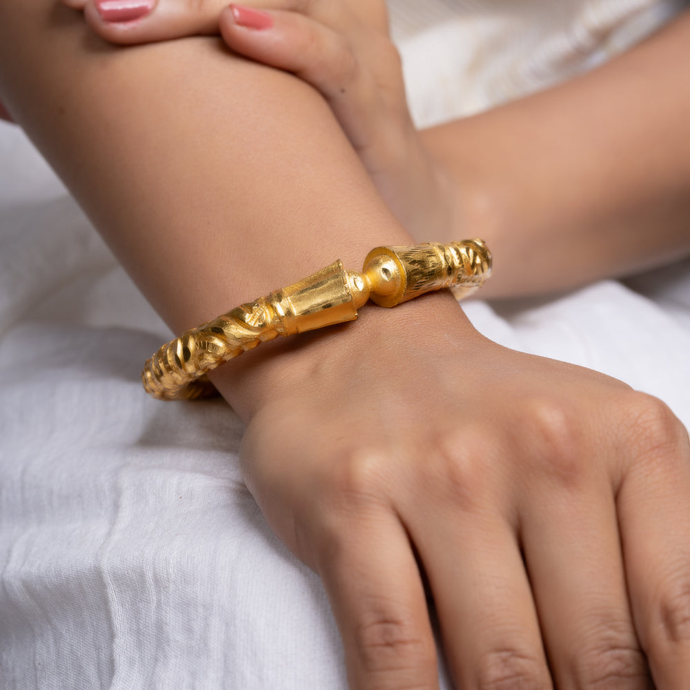 Gold plated bangle by LOOK AND ADORN on a womans wrist ornate textured design in gold tone