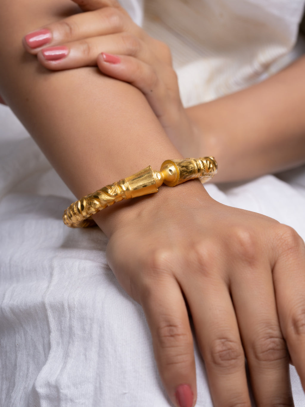 Gold plated bangle by LOOK AND ADORN on a womans wrist ornate textured design in gold tone