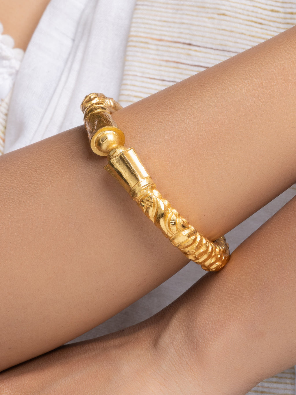 LOOK AND ADORN gold plated bangle on wrist featuring ornate textured tube design and polished finish