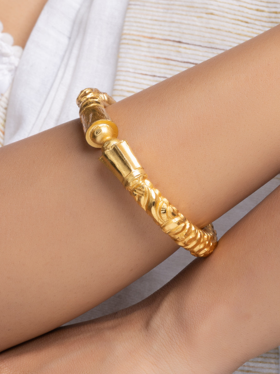 LOOK AND ADORN gold plated bangle on wrist featuring ornate textured tube design and polished finish