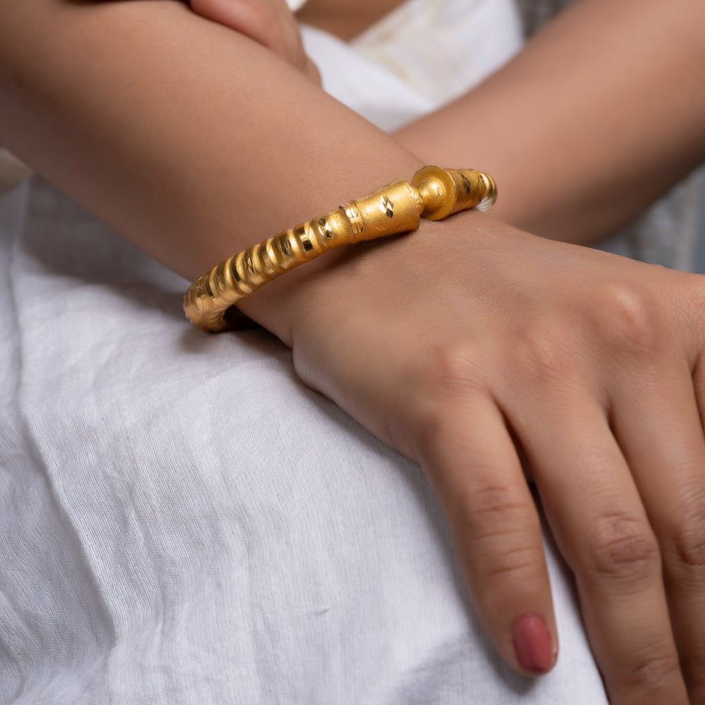 LOOK AND ADORN gold plated bangle on a model wrist with textured bead details worn with white dress