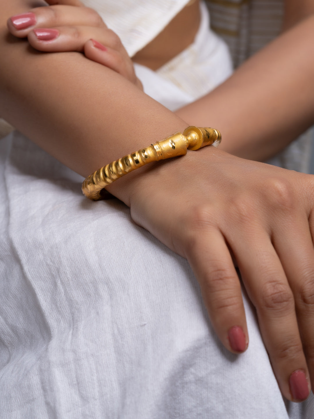 LOOK AND ADORN gold plated bangle on a model wrist with textured bead details worn with white dress