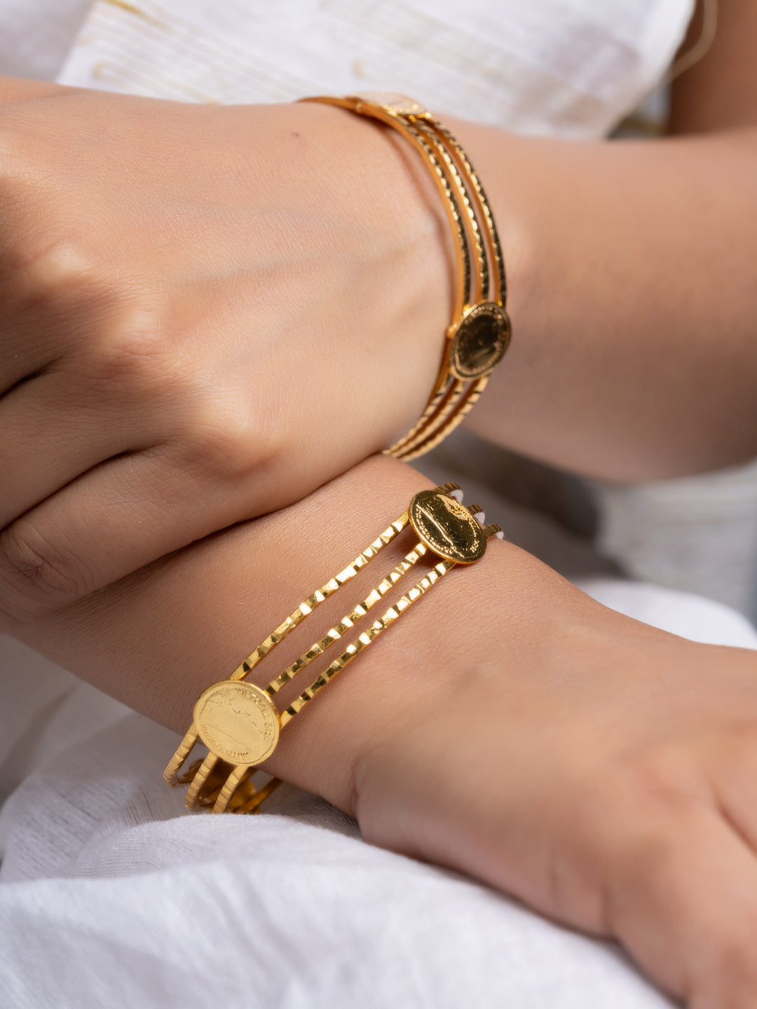 LOOK AND ADORN gold plated bangle set with stacked coin charms on female wrists styled with white linen