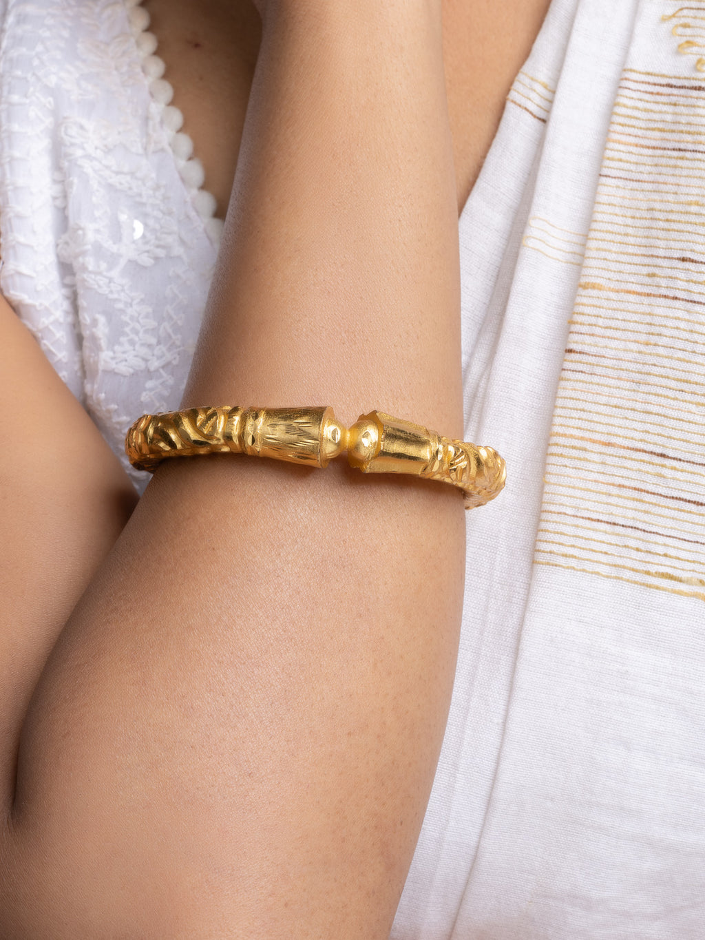 LOOK AND ADORN gold plated bangle on model arm with ornate textured design worn with white ethnic outfit