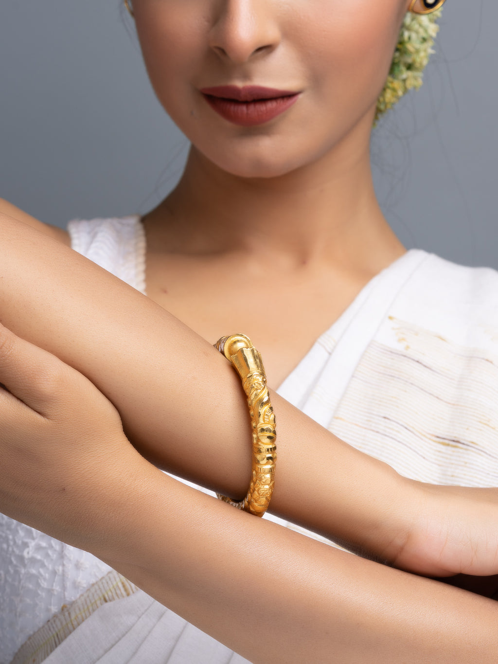 LOOK AND ADORN gold plated bangle on woman wearing white saree close up traditional jewelry