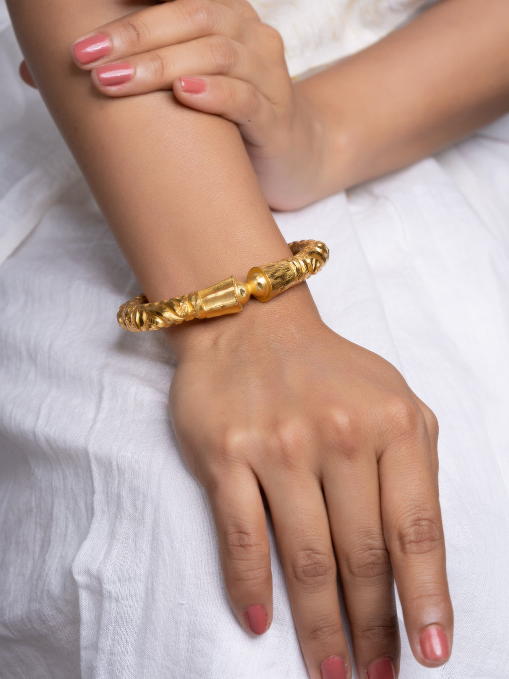 LOOK AND ADORN gold plated bangle on model wrist ornate twisted carved design styled with white dress