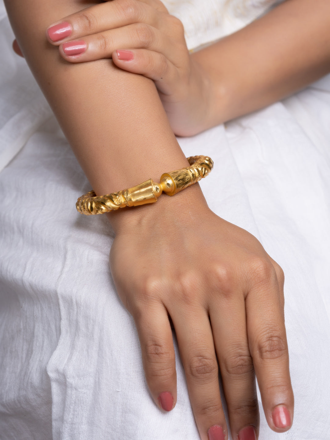 LOOK AND ADORN gold plated bangle on model wrist ornate twisted carved design styled with white dress