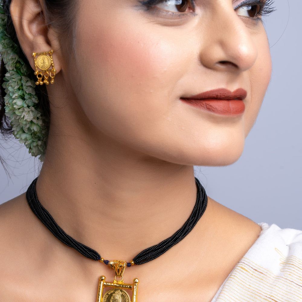 Woman wearing gold plated necklace set with black beaded chains and matching gold earrings