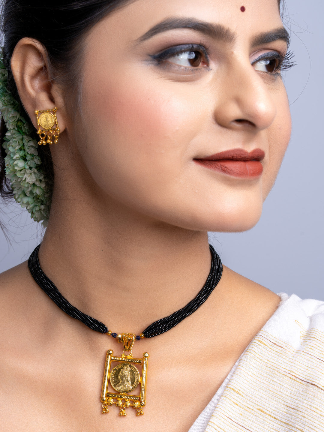 Woman wearing gold plated necklace set with black beaded chains and matching gold earrings