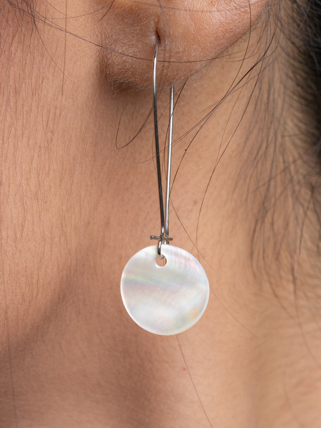 Close-up of a handmade german silver choker necklace with a round white pendant worn on the ear