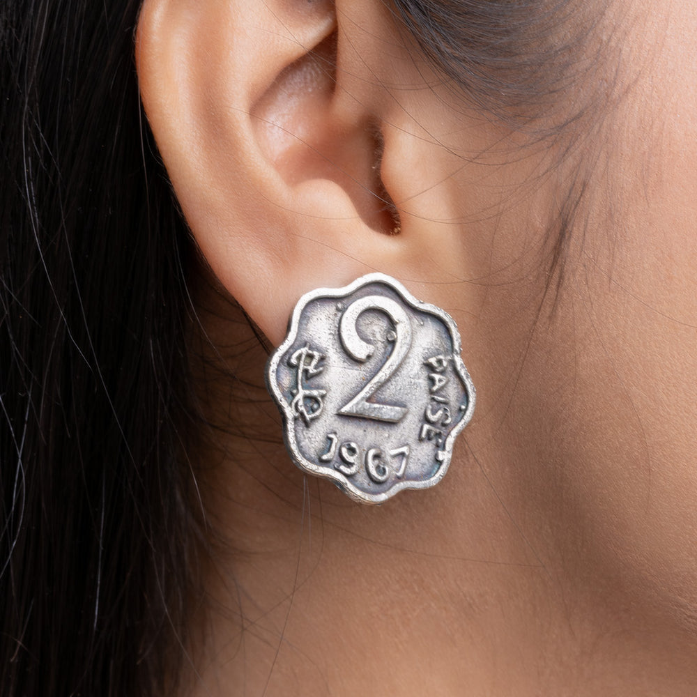 Close-up of oxidised silver earrings designed like a vintage 2 paise coin worn on ear