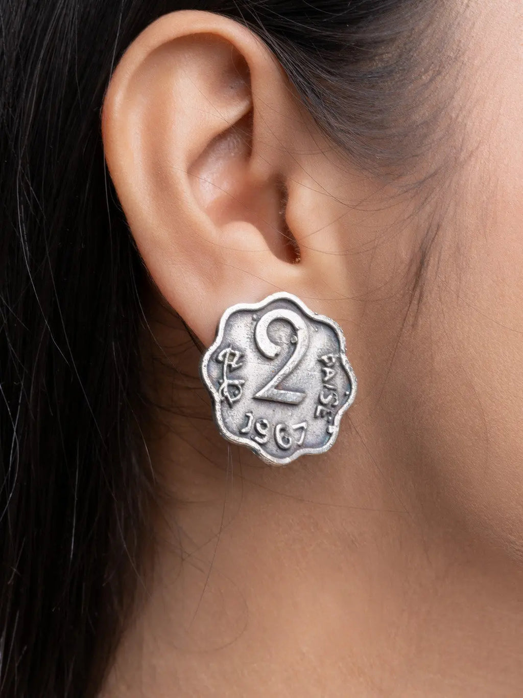 Close-up of oxidised silver earrings designed like a vintage 2 paise coin worn on ear