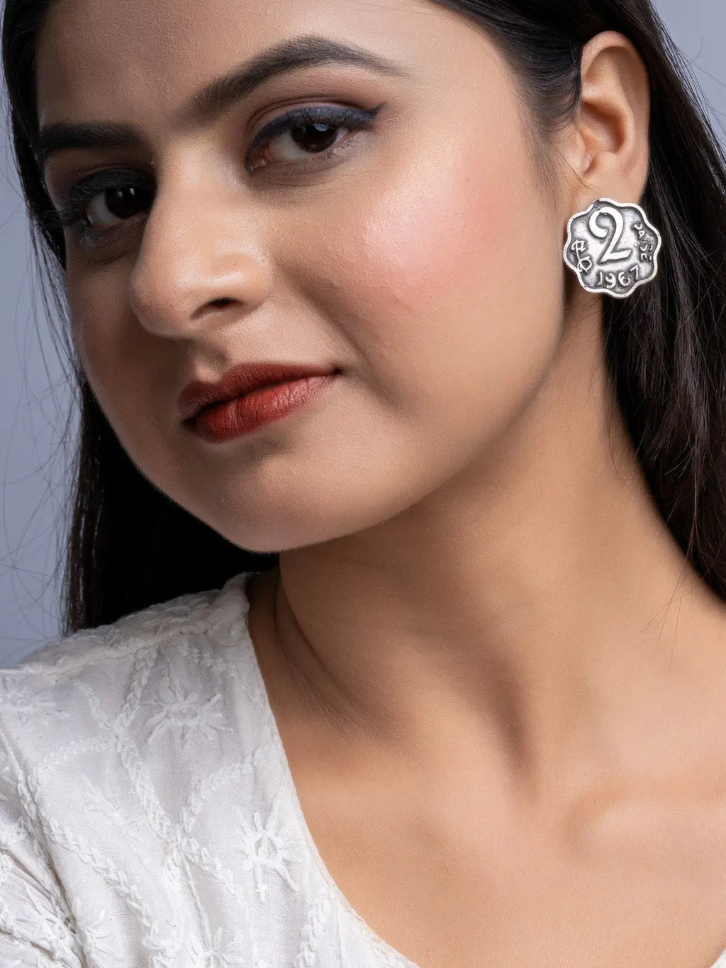 Close-up of woman wearing oxidised silver earrings with a vintage coin design by LOOK AND ADORN