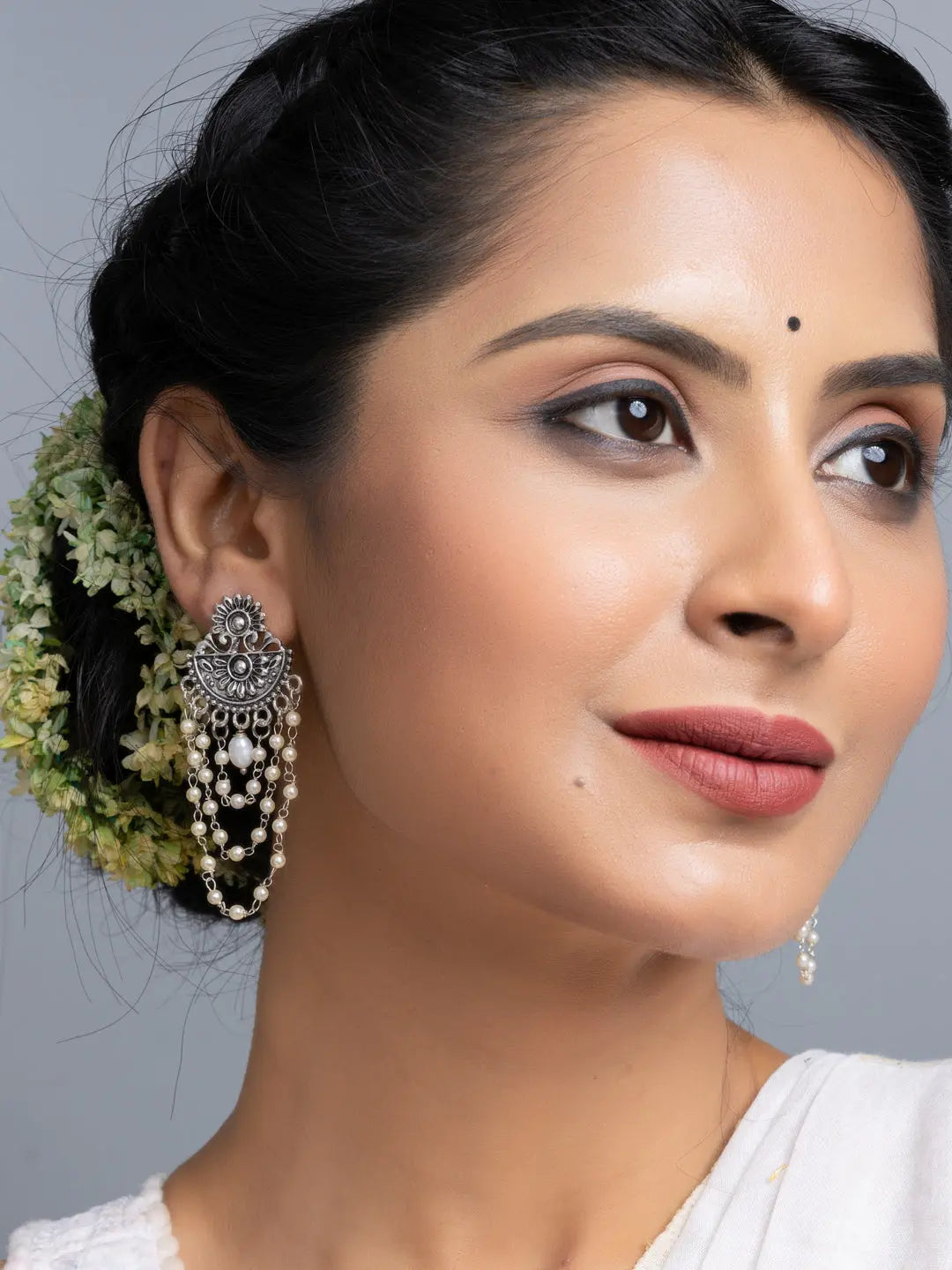 Close-up of woman wearing handmade pearl stud earrings with intricate silver design and dangling pearls
