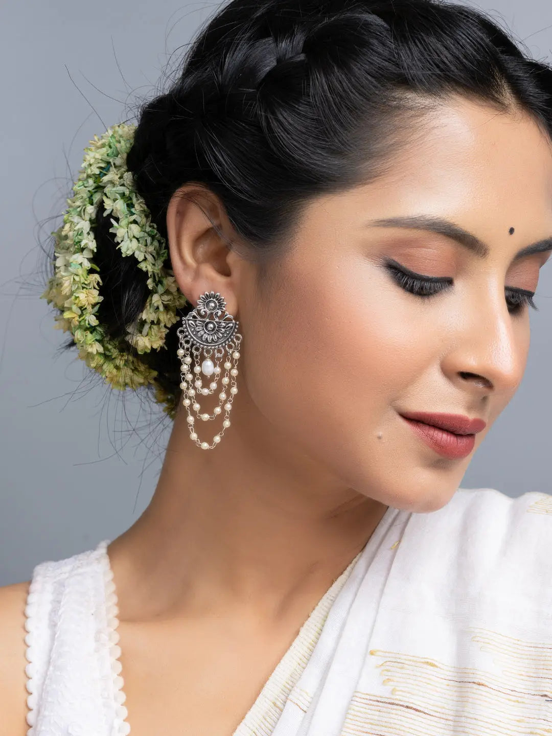 Handmade pearl stud earrings with intricate design worn by woman in traditional attire