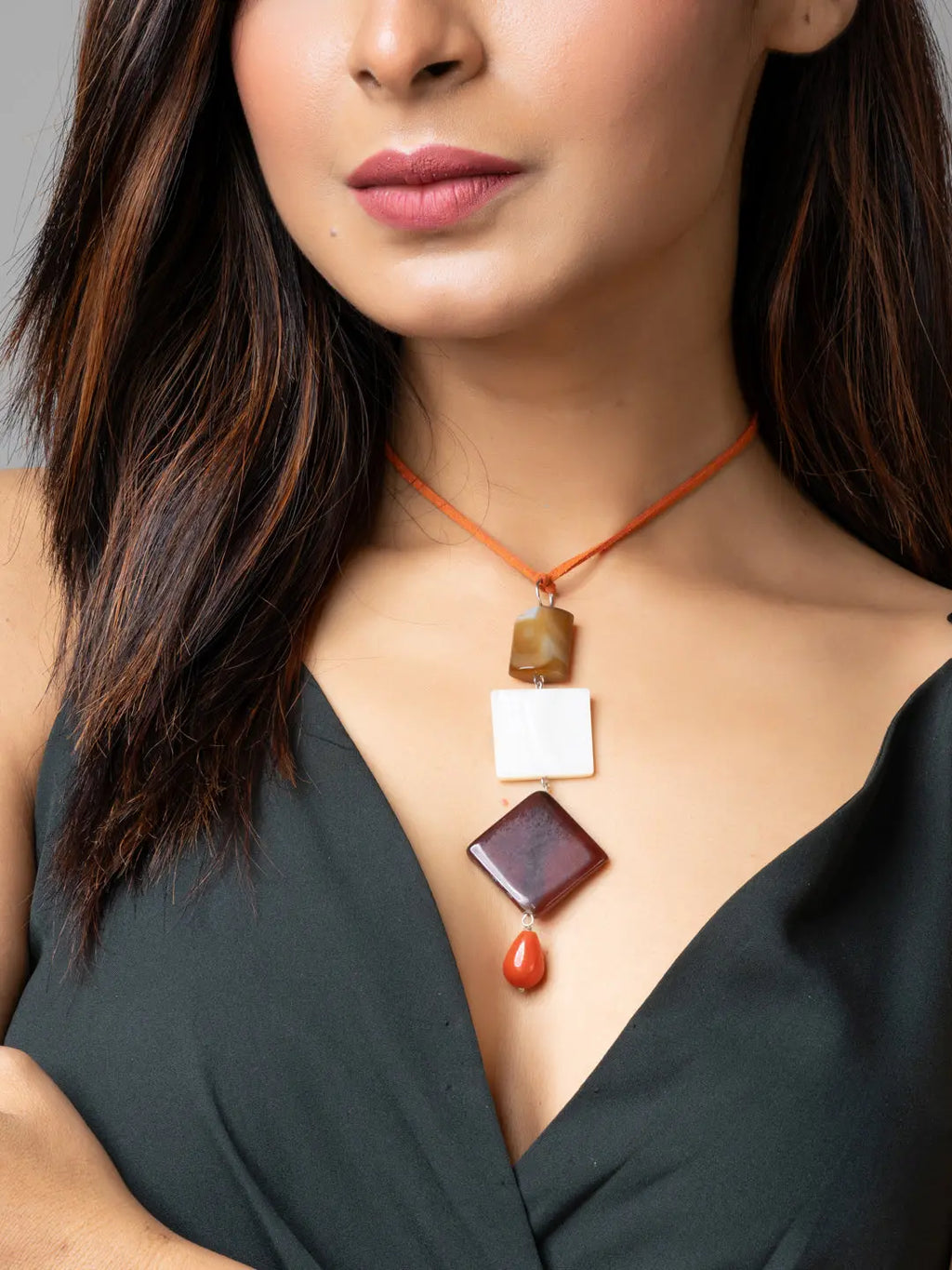 Handmade mother of pearl necklace with geometric stone pendants worn by woman in black dress