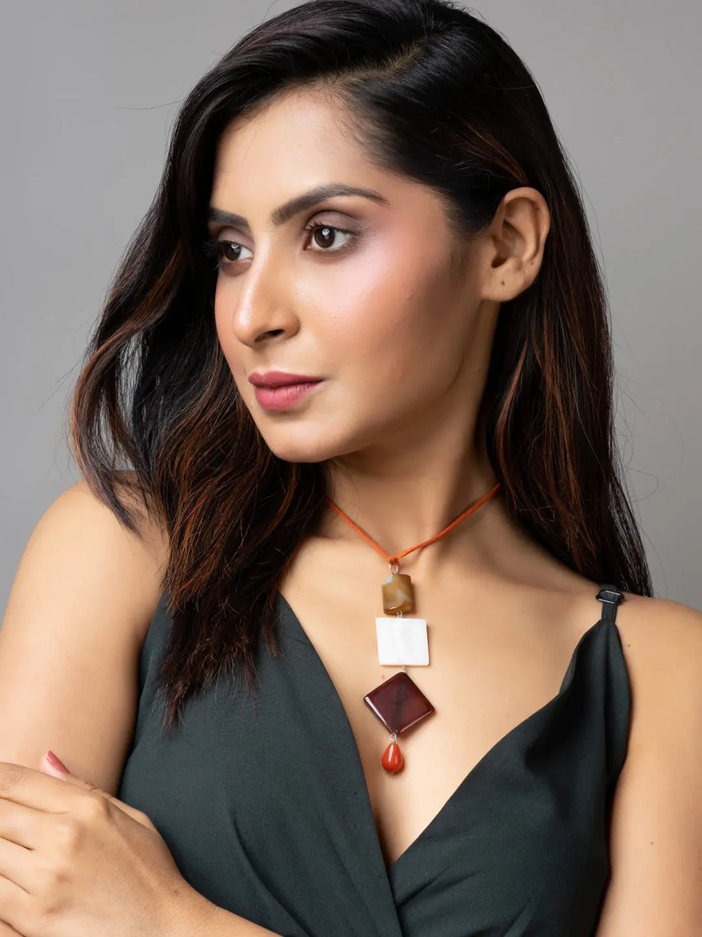 Handmade mother of pearl necklace with geometric pendants worn by woman in black top