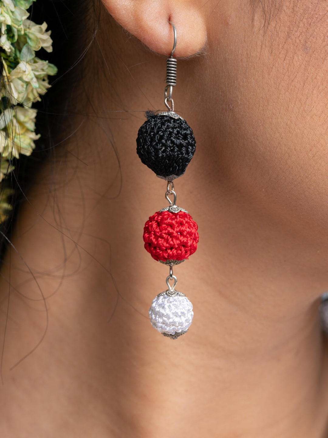 Handmade Black Red Earrings with black, red, and white crochet balls hanging on an ear