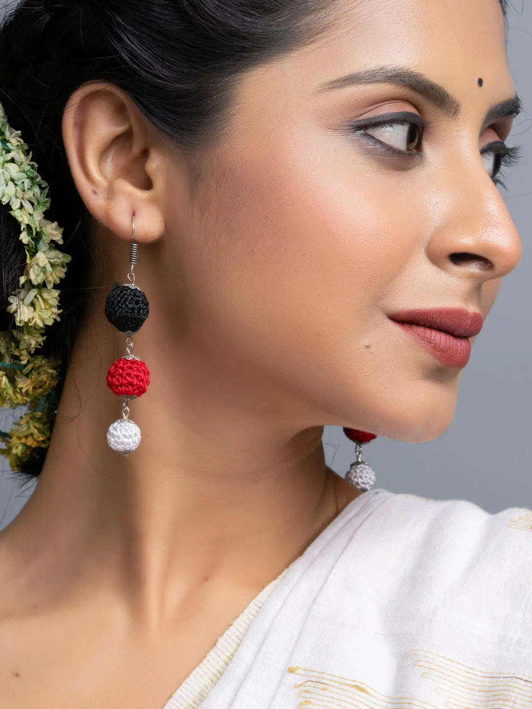 Handmade Black Red Earrings with black, red, and white crochet beads worn by a woman in white attire