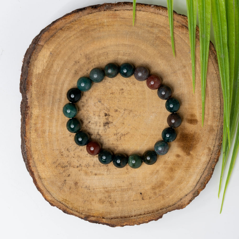 Stylish blood stone bracelet made with polished beads, displayed on a wooden base