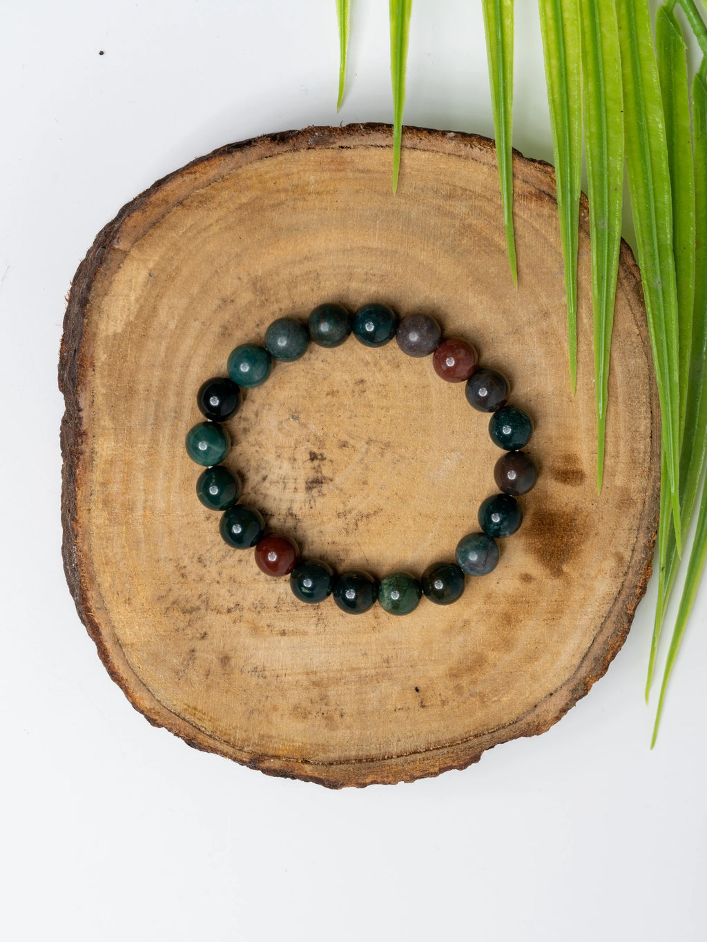 Stylish blood stone bracelet made with polished beads, displayed on a wooden base