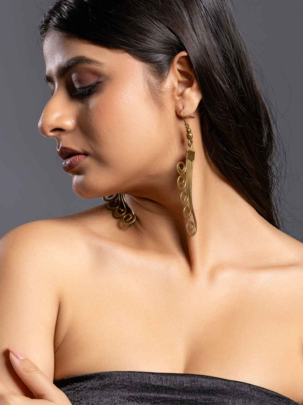 Elegant brass earrings in a swirling design, showcasing a unique Dokra jewelry style