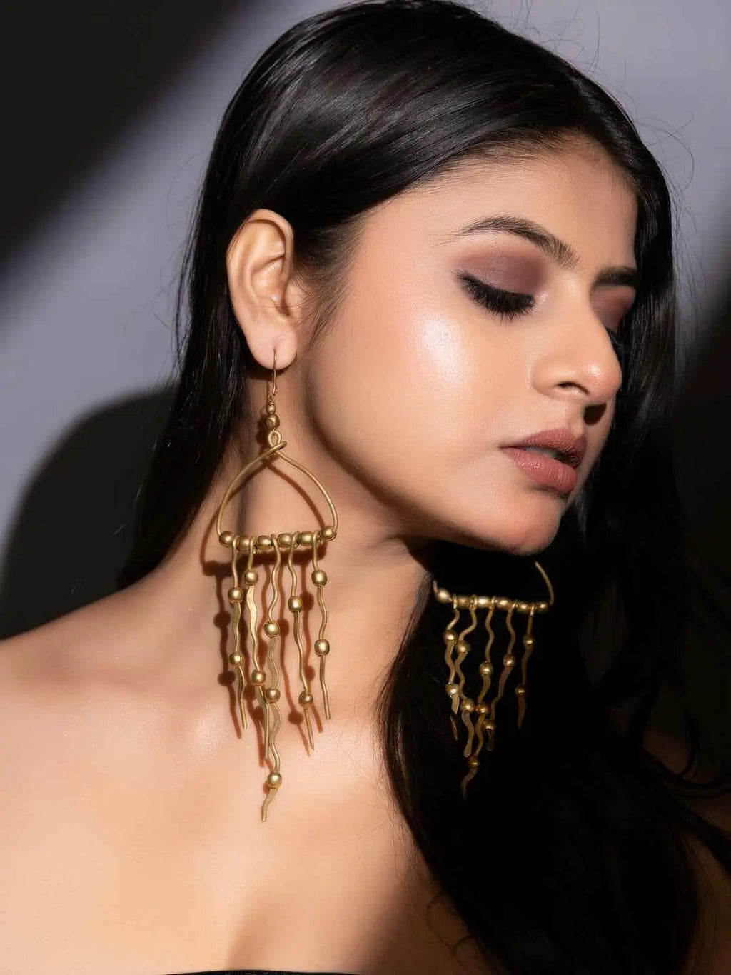 Dokra brass earrings with intricate design and dangling gold-tone beads, perfect for a statement look