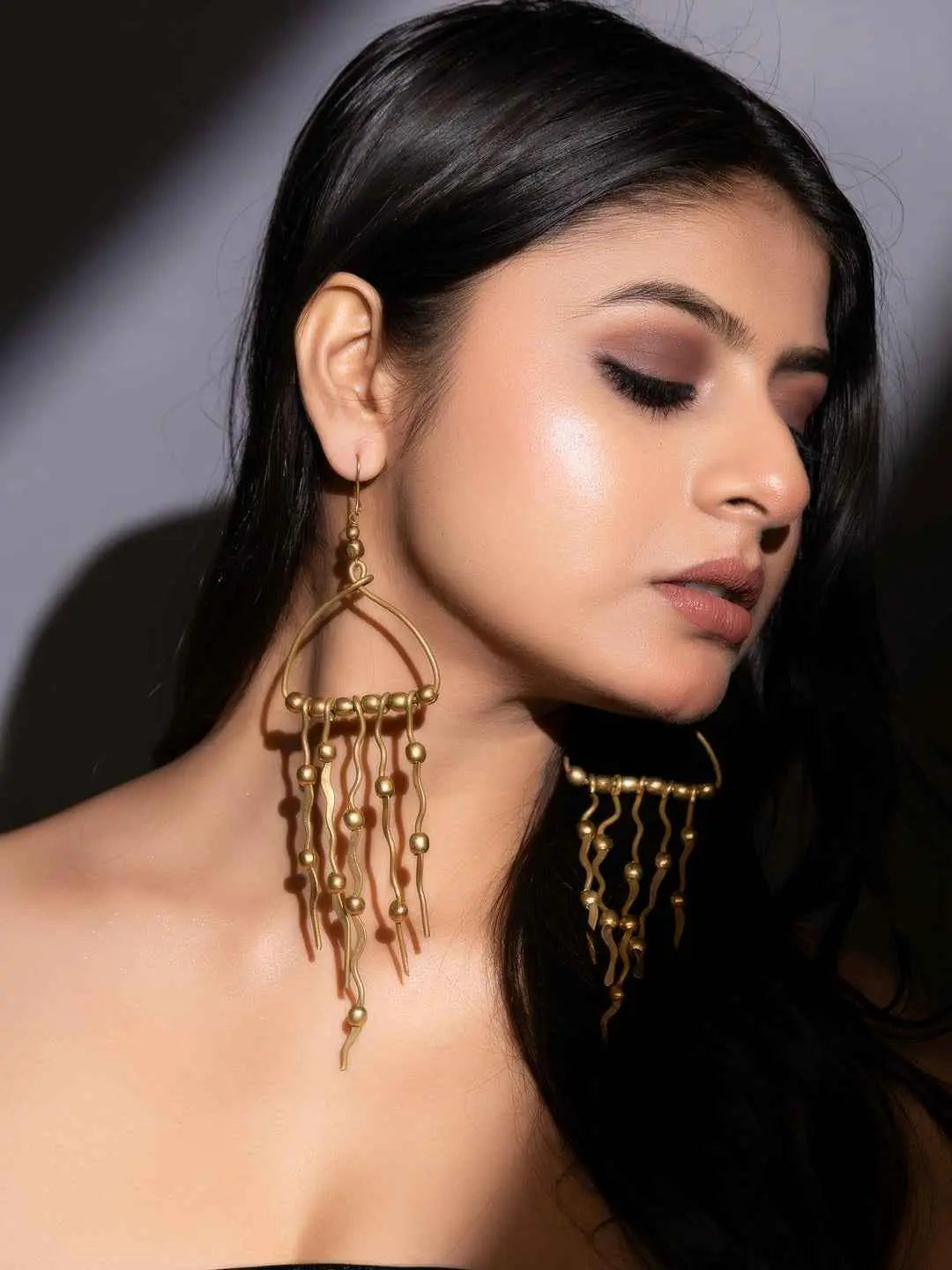 Dokra brass earrings with intricate design and dangling gold-tone beads, perfect for a statement look