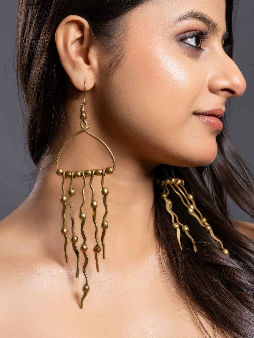 Dokra brass earrings with unique abstract design and cascading metal beads in a warm antique finish