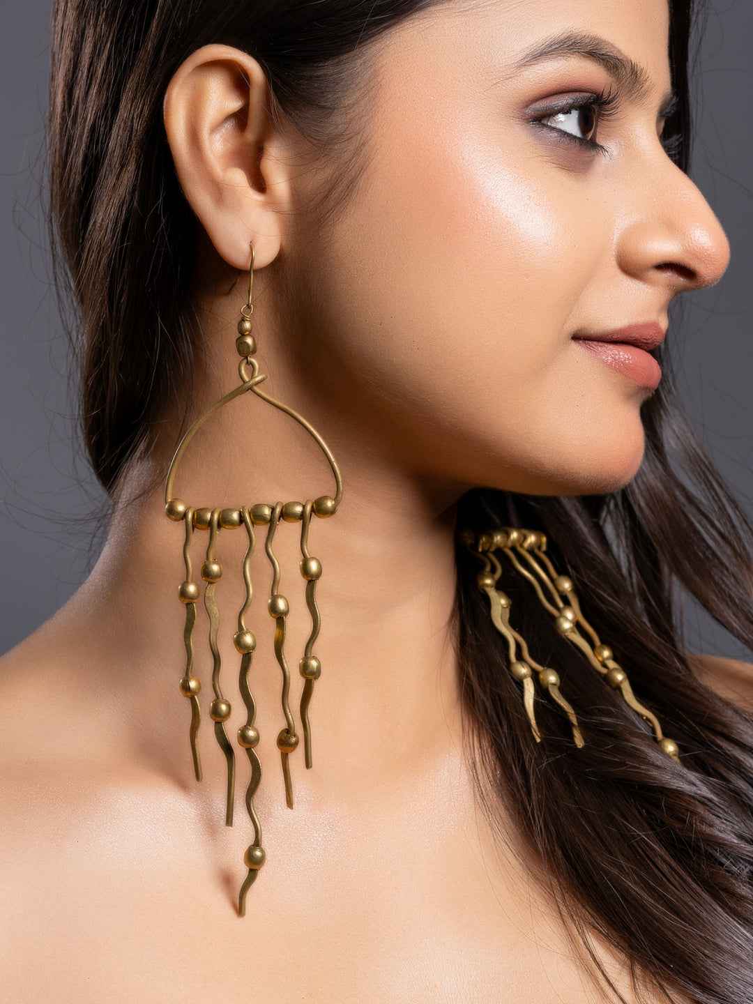 Dokra brass earrings with unique abstract design and cascading metal beads in a warm antique finish