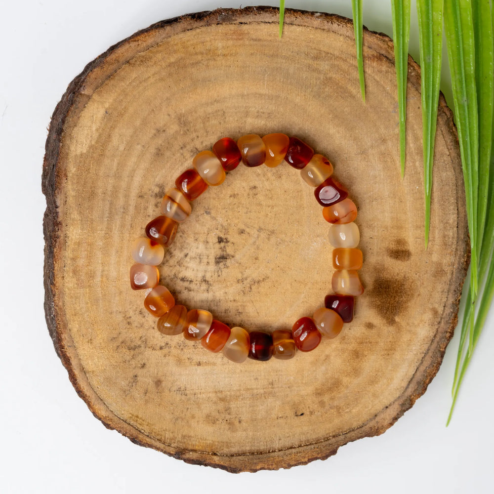 Carnelian bracelet on a wooden slice background showcasing vibrant orange and red gemstones