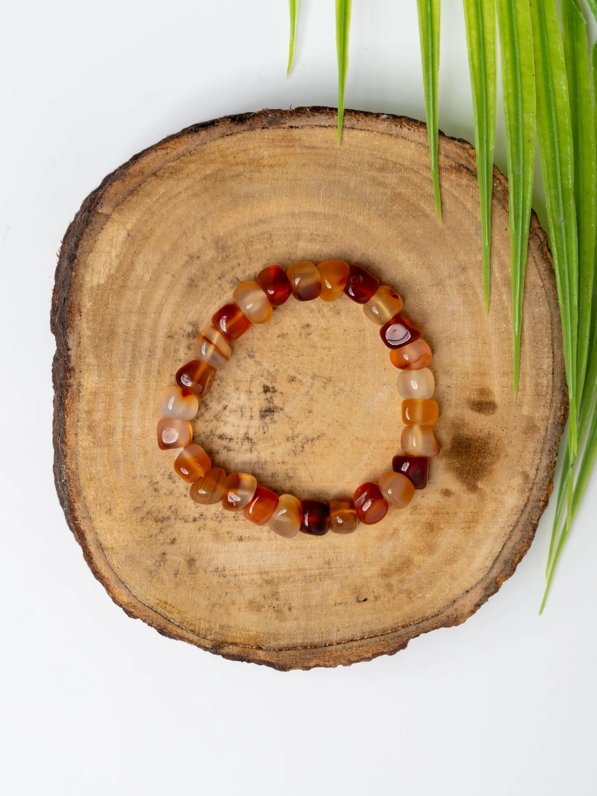 Carnelian bracelet on a wooden slice background showcasing vibrant orange and red gemstones