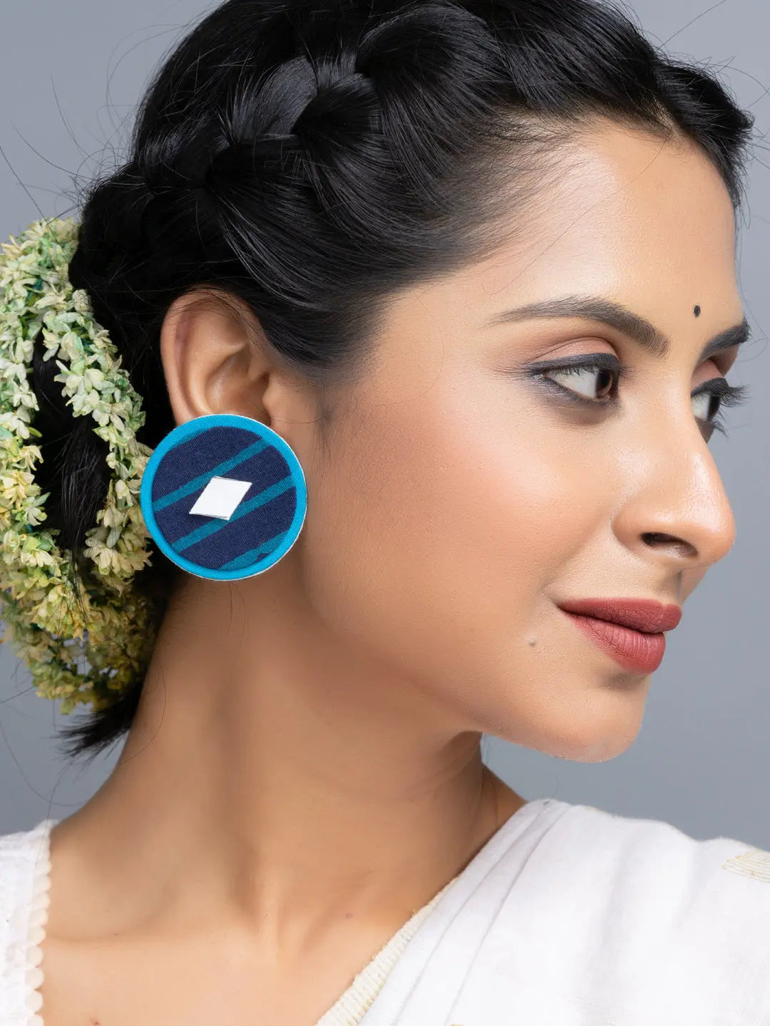 Handmade fabric earrings in blue worn by woman with braided hair and traditional attire