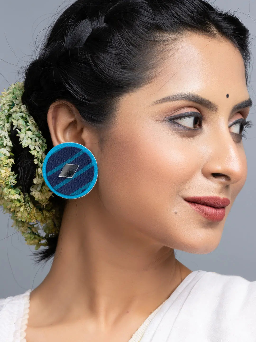 Woman wearing blue circular fabric earrings handmade by LOOK AND ADORN with geometric design