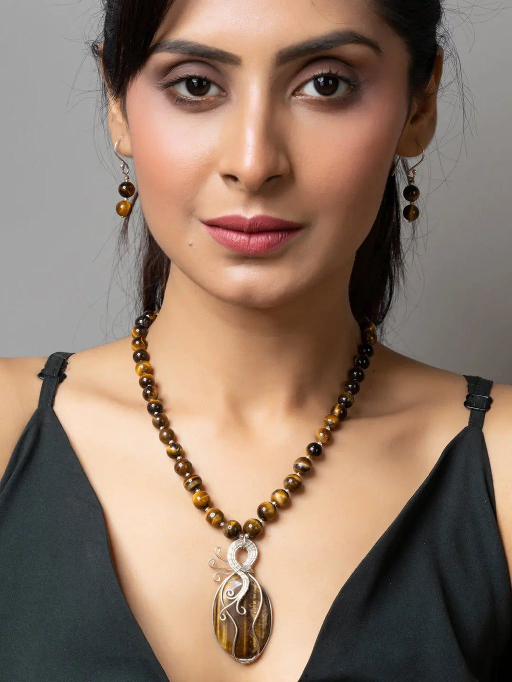 Woman wearing a handmade tiger eye necklace with matching earrings by LOOK AND ADORN