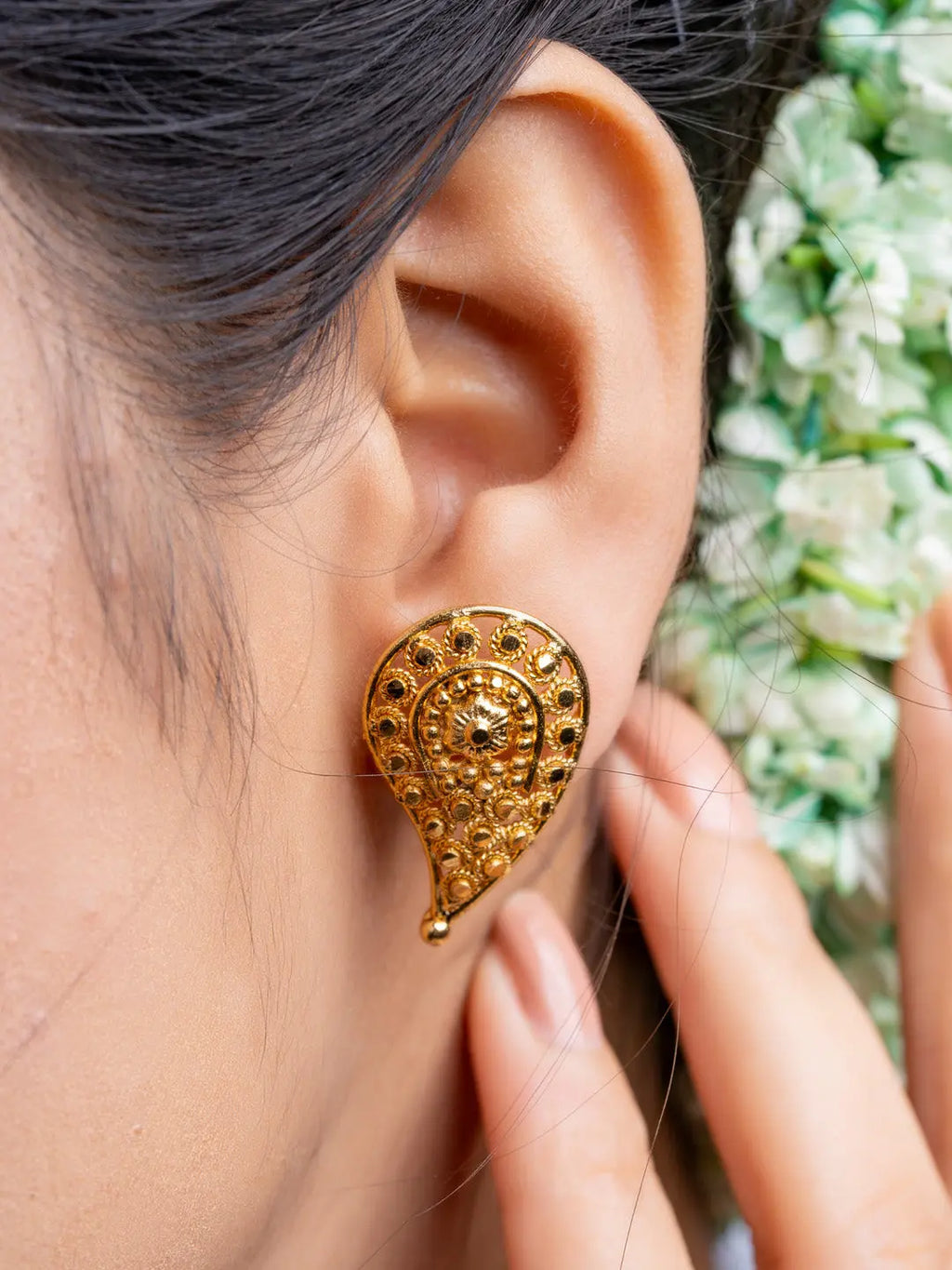 Gold plated intricate designer earring worn on ear showcasing elegant traditional jewelry style