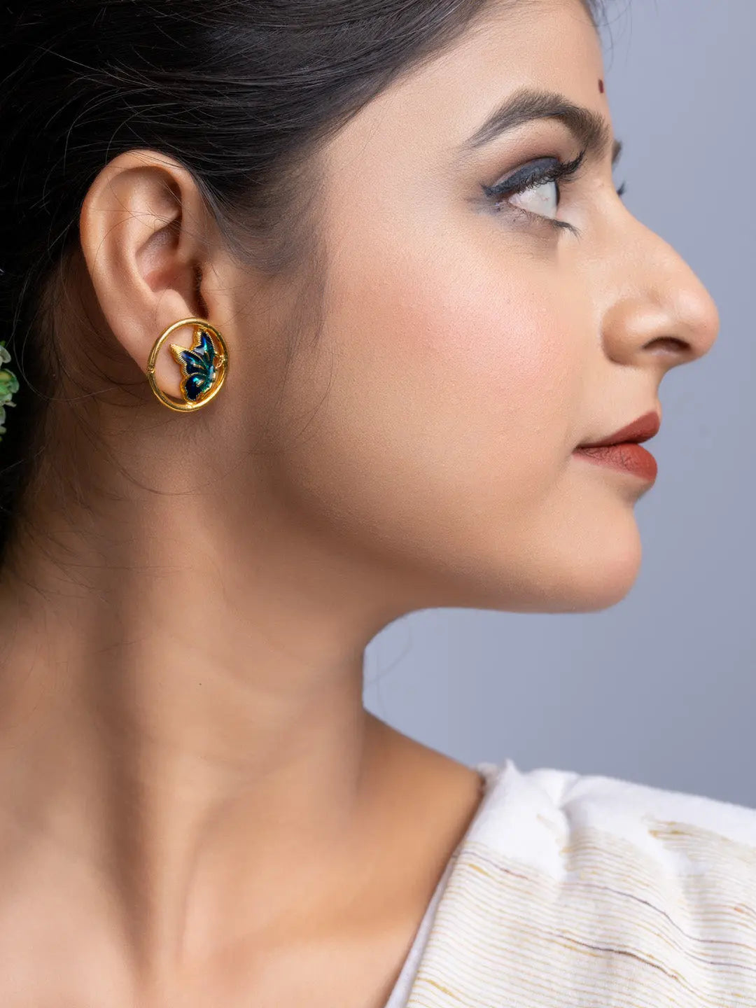 Close-up of woman wearing elegant gold plated earrings with blue accents from LOOK AND ADORN