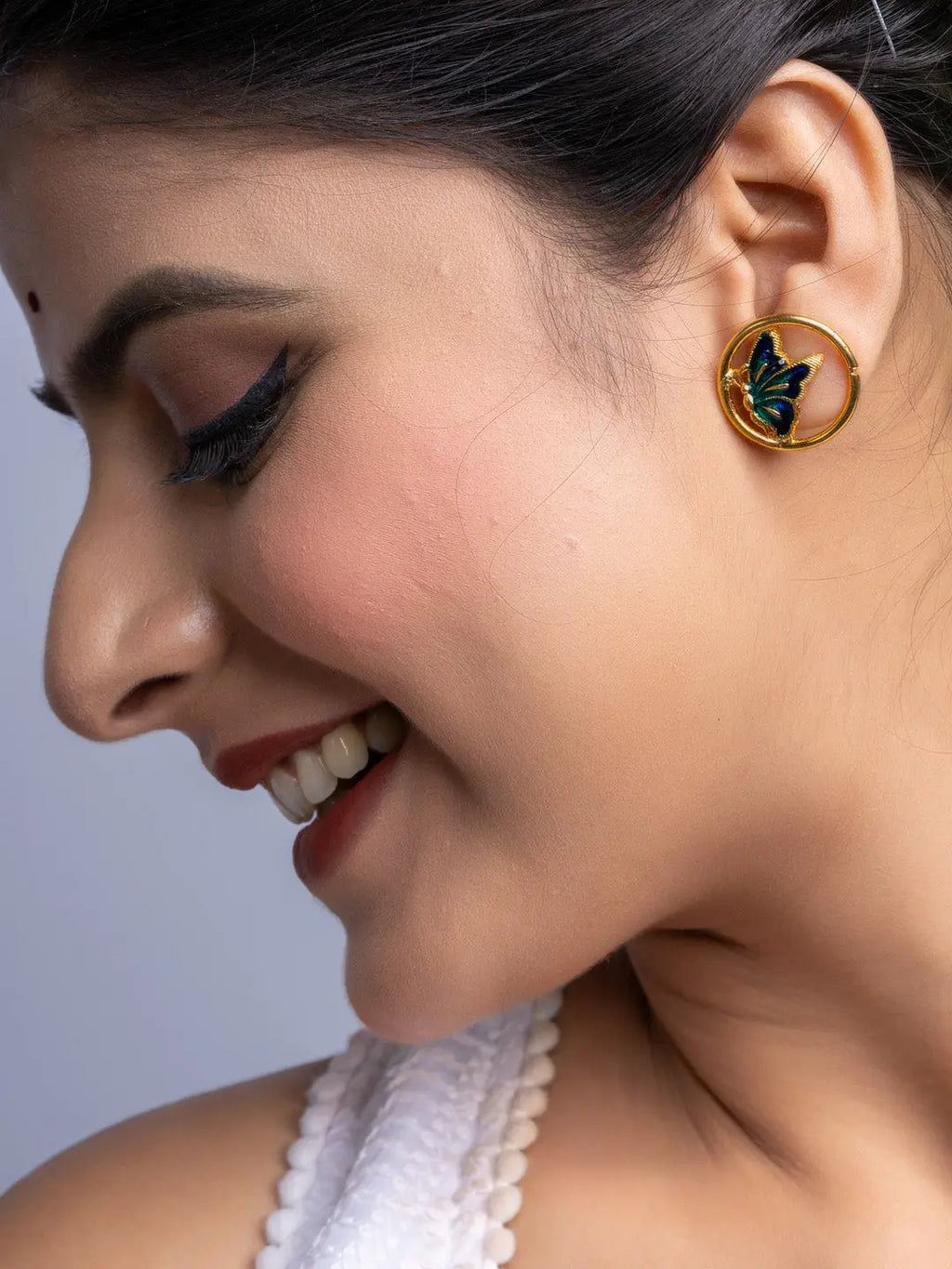 Close-up of woman wearing gold plated earrings with butterfly design from LOOK AND ADORN