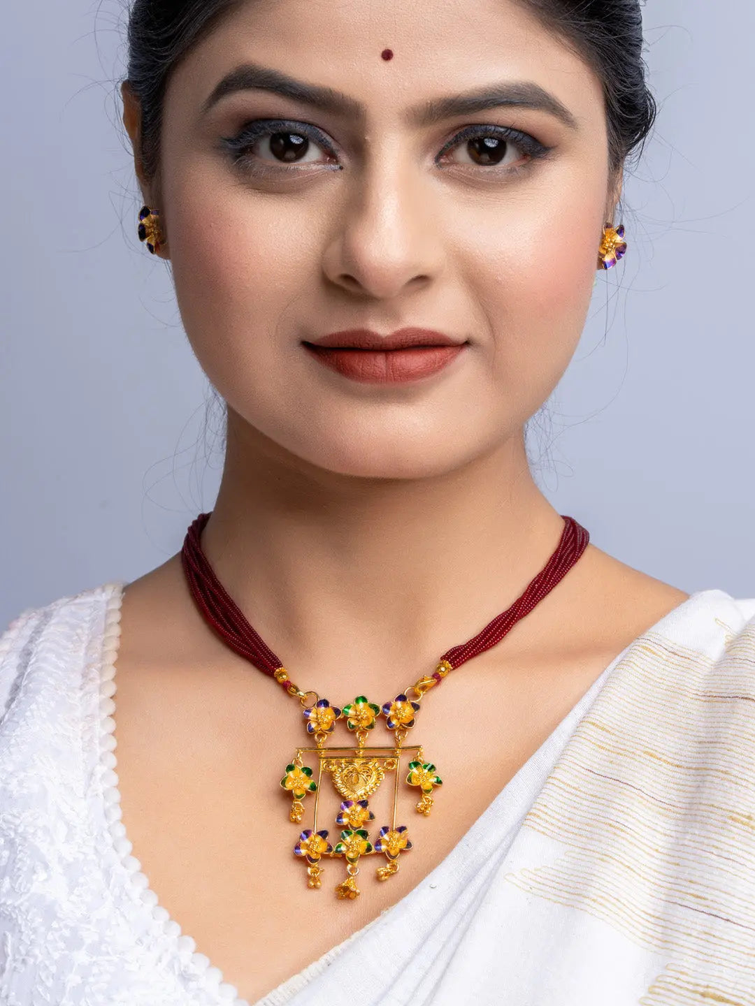 LOOK AND ADORN gold plated necklace with floral design and matching earrings on woman wearing white saree