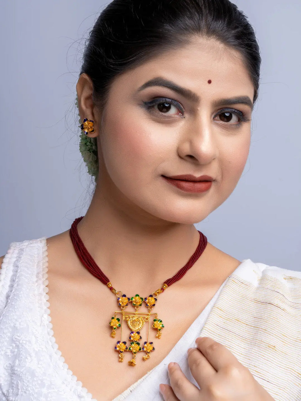 Woman wearing gold plated floral necklace and matching earrings from LOOK AND ADORN