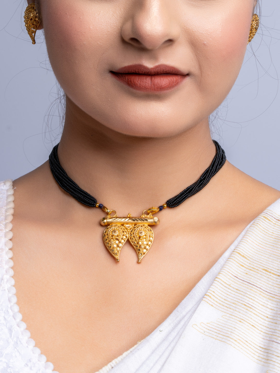 LOOK AND ADORN gold plated necklace with black beads and intricate leaf pendant on model
