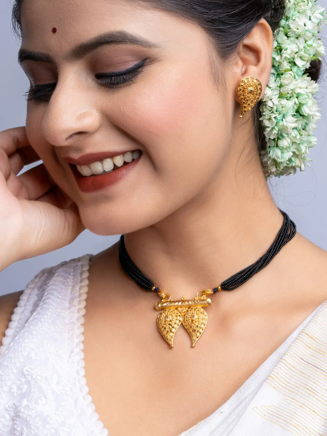 Woman wearing gold plated necklace and earrings set from LOOK AND ADORN with black beaded chain and intricate designs
