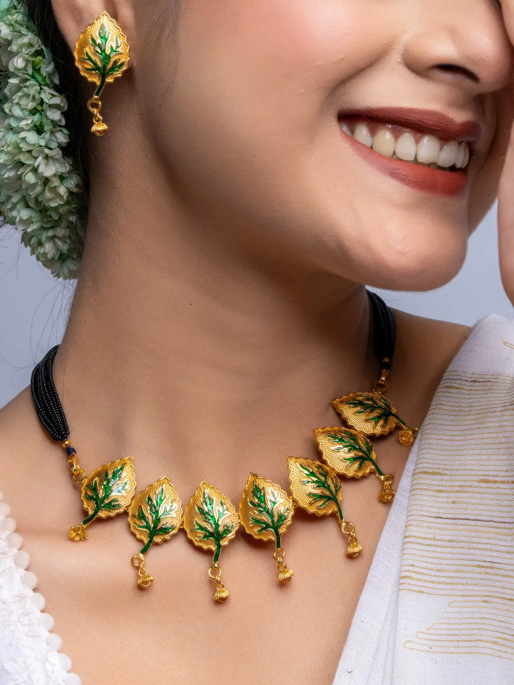 Gold plated leaf design necklace and matching earrings by LOOK AND ADORN on smiling woman