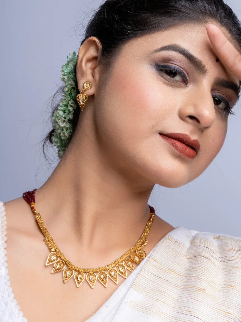 Elegant gold plated necklace set with matching earrings worn by woman in traditional attire