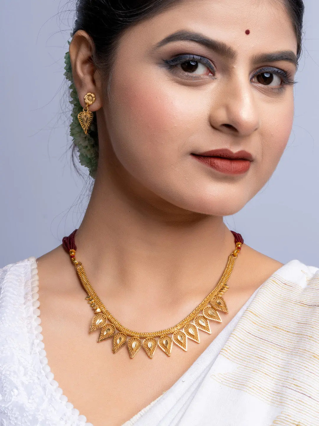Elegant gold plated necklace set worn by woman with matching earrings and traditional attire