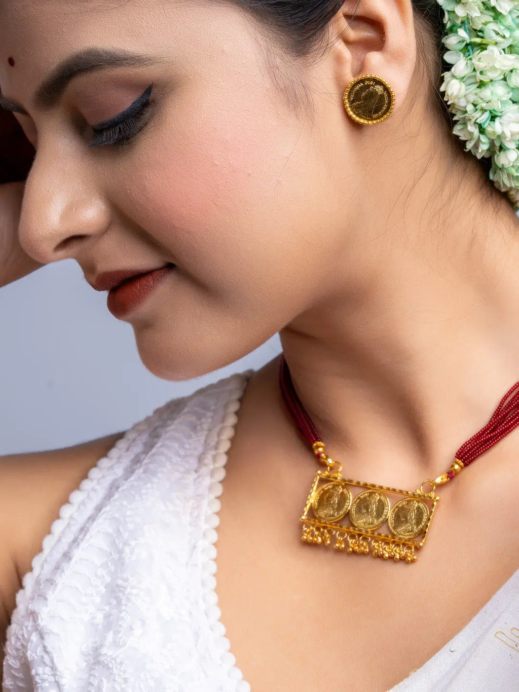 Gold plated necklace set with traditional pendant and matching earrings worn by woman