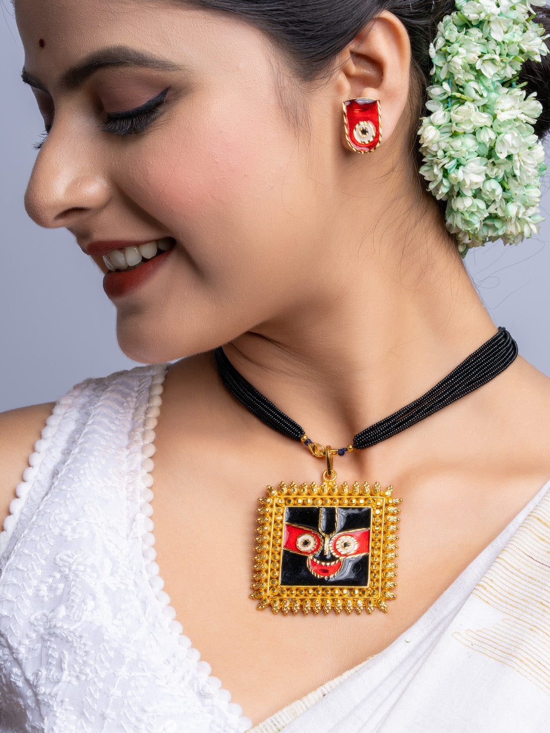 Gold plated necklace set with traditional pendant worn by woman in white saree and floral hair accessory
