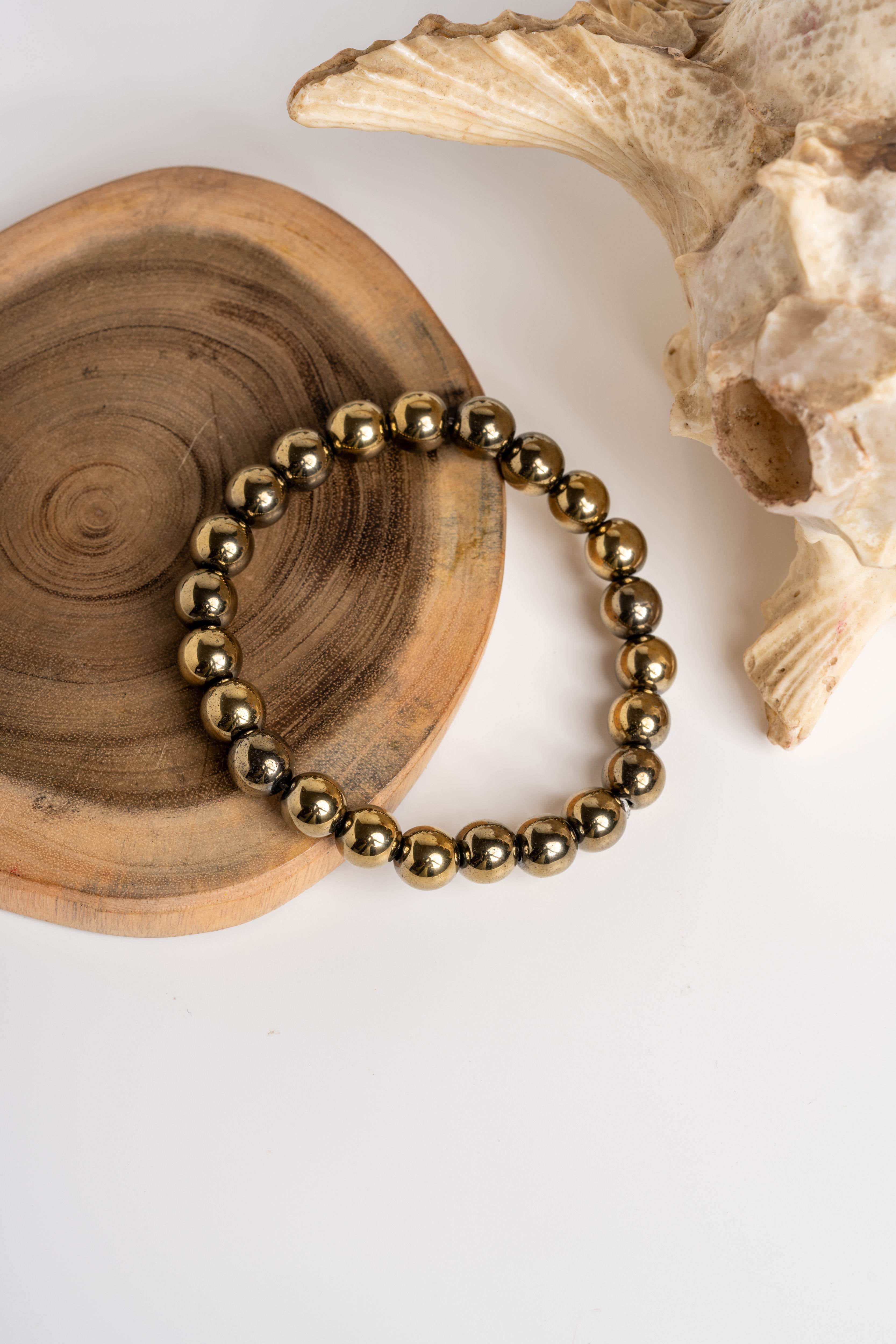 Golden Hematite Bracelet featuring polished beads on a wooden surface for elegant jewelry styling