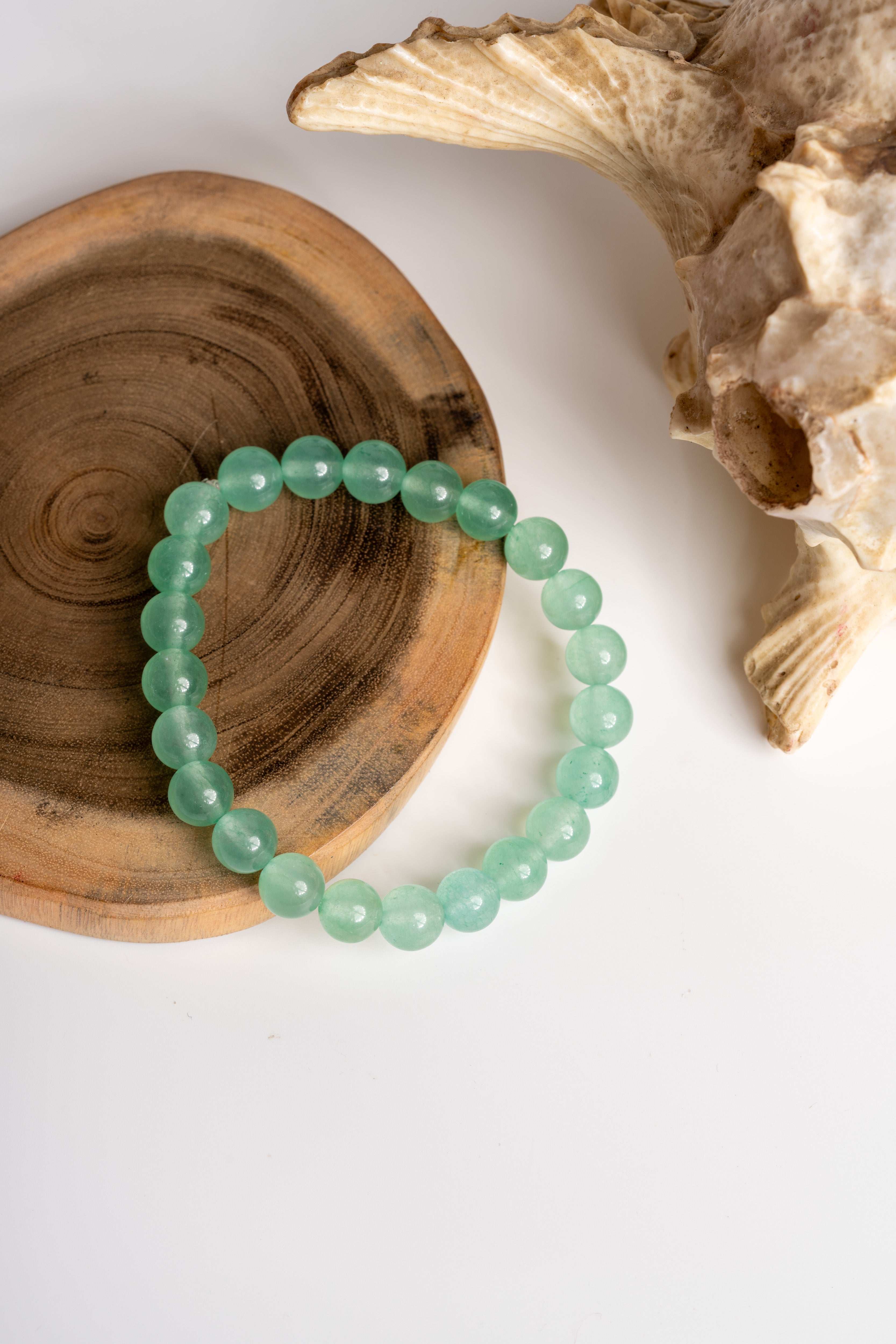 Green aventurine bracelet on a wooden surface, showcasing its smooth beads and elegant design